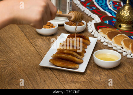 Gießen Honig auf Qatayef-traditionellen nahöstlichen Spezialitäten, die in der Regel in Muslime heiligen Monat Ramadan gegessen: Stockfoto