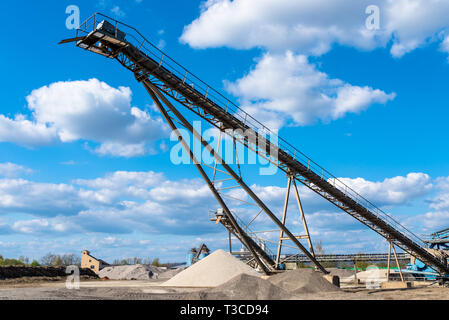 Förderband über Haufen von Kies auf blauen Himmel bei einem industriellen Zementwerk. Stockfoto