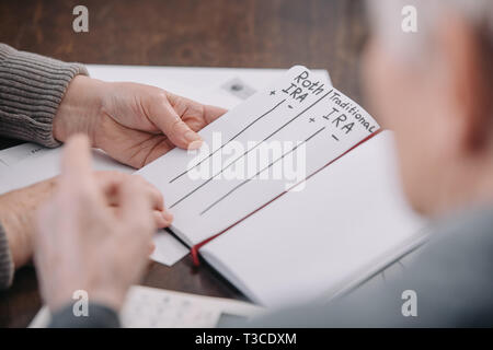 Senior Paar hält Notebook mit Roth IRA und traditionelle ira Worte Stockfoto