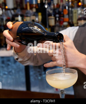 Barkeeper gießt Sekt im Glas Stockfoto