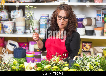Portrait von Frau florist tragen Schürze stehen an der Theke, Blumenstrauß für Client im Flower Shop. Stockfoto