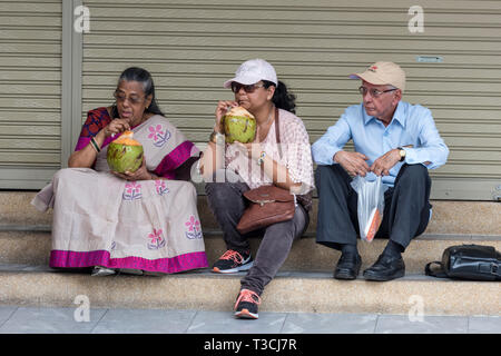 Eine Familie, die eine Pause an der Seite der Straße trinken frische Kokosnuss Saft von Muscheln in Bangkok, Thailand, Asien. Stockfoto