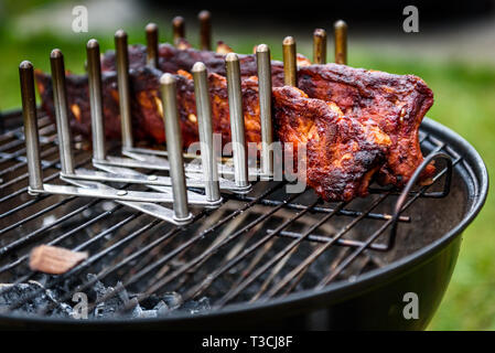 Baby zurück Spare Ribs Braten auf BBQ Grill Kugelgrill. Hausgemachte Schweinerippchen auf einem Grill mit geringe und langsame Methode. Grillen draußen in der Natur bei Fami Stockfoto