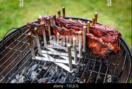 Baby zurück Spare Ribs Braten auf BBQ Grill Kugelgrill. Hausgemachte Schweinerippchen auf einem Grill mit geringe und langsame Methode. Grillen draußen in der Natur bei Fami Stockfoto