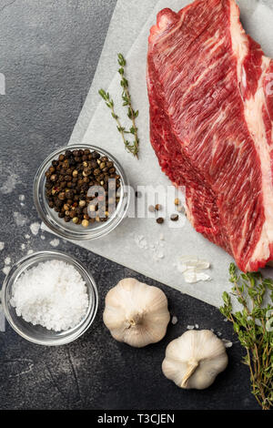 Makro, frisch von Rindfleisch auf grauem Hintergrund mit Kräutern, Salz und Pfeffer auf konkreten Hintergrund. Freier Platz für Text. Ansicht von oben. Konzept der frischen fo Stockfoto