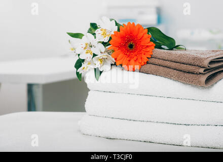 Ruhige Szene mit Handtüchern und Blumen im Spa. Weiße Handtücher, Aromatherapie und Wellness Behandlung Stockfoto