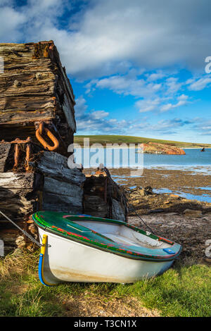 Holz- Stapel und Strände Yacht durch die Churchill Barrier und blockship zwischen Burray und Blick Holm, Orkney Inseln. Stockfoto