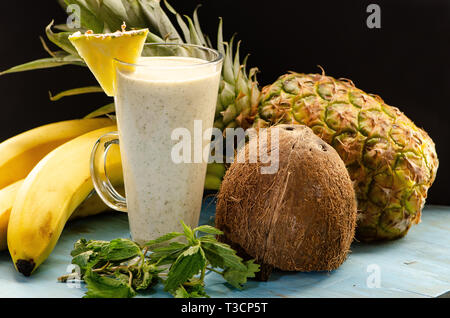 Smoothie mit Ananas, Bananen, Brennesseln und Kokosmilch auf einem hellen Blau Holzbrett Stockfoto