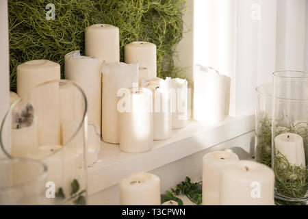 Viele Kerzen und Blüten der Trauung zu feiern. Dekorative Kerzen auf dem Tisch an sonnigen Licht. Wachs Kerze als Weihnachtsschmuck oder Spa Stockfoto