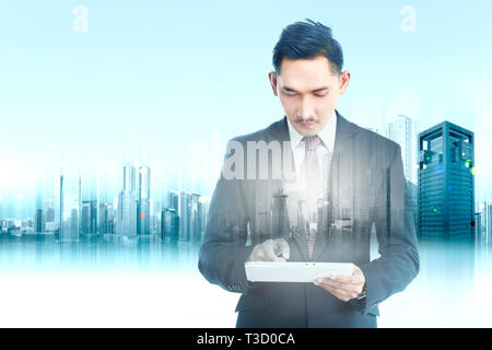 Double Exposure der modernen Stadt und stattliches asiatische Geschäftsmann mit digitalen Tablet in der Hand. Zukunft Technik Konzept Stockfoto