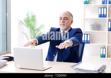 Alter Geschäftsmann Yoga Übungen im Büro Stockfoto