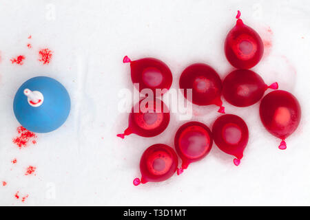 Kleine Kugeln gefüllt mit roter Farbe liegen auf dem Schnee zum Spielen in der Wintersaison Stockfoto