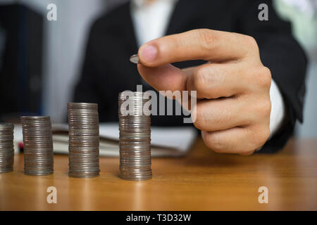 Geschäftsmann nimmt Münzen auf den Tisch und zählt Geld. Geschäftskonzept. Stockfoto