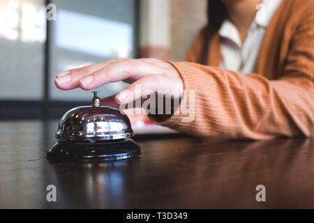 Frauen rufen Sie das Hotel an der Rezeption mit dem Finger drücken Sie eine Glocke in der Lobby Hotel. hotel Konzept. Stockfoto