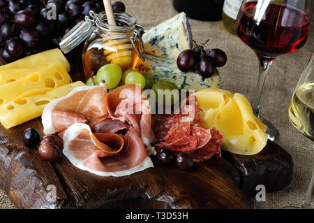 Antipasto catering Plattenteller mit ruckartiger Speck, Schinken, Salami, Käse und Trauben auf einem hölzernen Hintergrund Stockfoto