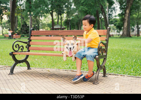 Kinder und Hunde im Freien. Asiatische Junge genießen und Spielen im Park mit seinem liebenswerten Pembroke Welsh Corgi. Stockfoto