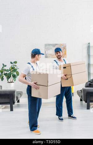 Zwei movers in Uniform, die Kartons in der Wohnung mit Platz kopieren Stockfoto