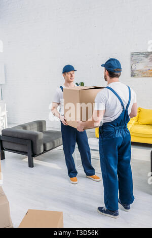 Zwei movers in Uniform Transport Karton im Wohnzimmer Stockfoto