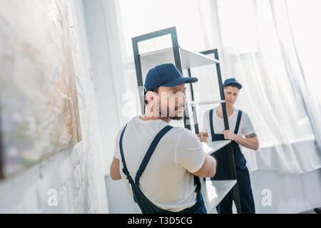 Zwei movers in Uniform Transport Rack in der Wohnung mit Platz kopieren Stockfoto