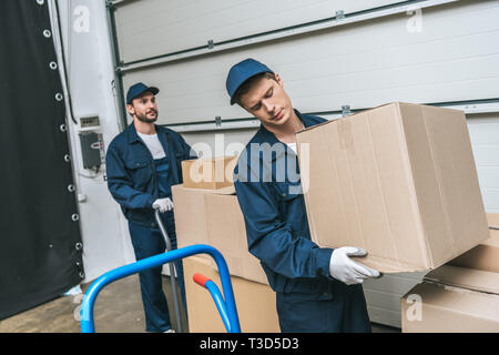 Zwei konzentrierte movers in Uniform Transport von Kartons in Lager Stockfoto