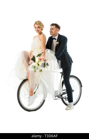 Schöne Braut Holding wedding bouquet, während auf dem Fahrrad sitzen zusammen mit Bräutigam isoliert auf weißem Stockfoto