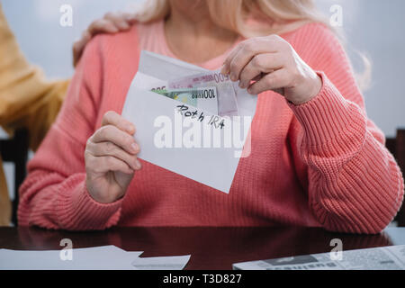 Teilweise mit Blick auf die Frau mit Umschlag mit "Roth IRA" Schriftzug und Geld Stockfoto