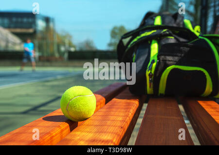 Tennis ball und Sport Tasche auf der Bank auf Gericht. Konzept für Sport, gesunde Lebensweise. Stockfoto