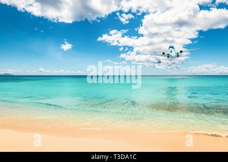 Airliner im Abstand oberhalb des wunderschönen Karibischen Meer, Land an Maho Beach in St Maarten - Saint Martin. Stockfoto