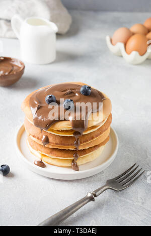 Süße hausgemachte Stapel Pfannkuchen mit Schokolade und Heidelbeeren auf weißer Tisch. Close Up. Stockfoto