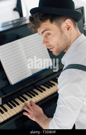 Selektiver Fokus der gut aussehende Pianist in stilvolle Kleidung Klavier spielen zu Hause Stockfoto