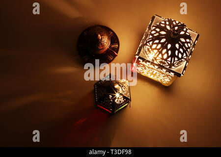 Festliche Tafel Zusammensetzung der glühenden Marokkanischen dekorative Laternen und bronze Tee Tasse. Dekorative goldenen Schatten. Grußkarte, Einladung für muslimische Stockfoto