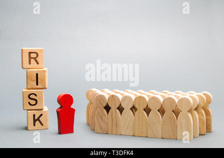 Holzblöcke mit dem Wort Risiko und eine Mannschaft mit einem Führer. Das Konzept der Teamarbeit, Krise, Lösung und Problem Management. Unternehmensplanung. In Stockfoto