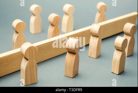 Holzfiguren von Menschen sind durch eine Barriere getrennt. Soziale Klassen. Der Wettbewerb zwischen den Teams. Das Konzept von Missverständnissen. Eine Schranke in Bezug Stockfoto