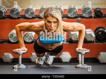 Körperlich fit Frau Liegestütze auf Hanteln in einem Health Club. Stockfoto