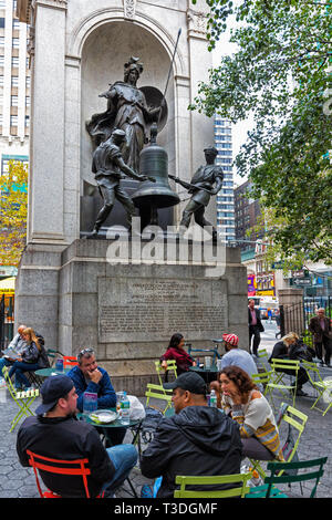 Herald Square, New York City, New York State, USA. Menschen entspannen im Café im Freien Tische. Hinter ihnen die Gedenkstätte für James Gordon Bennett, 1795 - Stockfoto