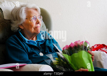Eine ältere Frau mit einem Blumenstrauß, weinen, traurig und einsam - Johannes Gollop Stockfoto