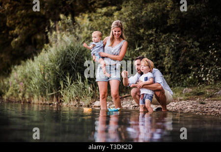 Junge Familie mit 2 Kleinkind Kinder draußen am Fluss im Sommer spielen. Stockfoto