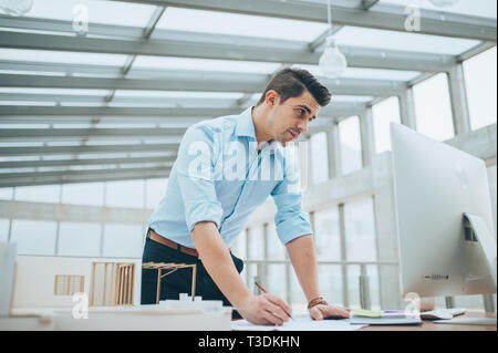 Junge Unternehmer oder Architekten mit Modell eines Hauses steht im Büro, arbeiten. Stockfoto