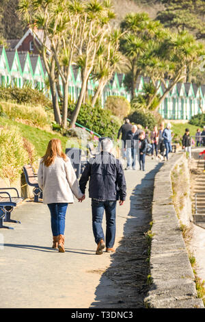 LANGLAND BAY, Gower, WALES - Februar 2019: Mann und Frau gehen Hand in Hand entlang der Promenade im Sonnenschein in Langland Bay auf der Gower Peninsula Stockfoto