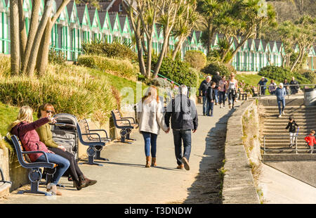 LANGLAND BAY, Gower, WALES - Februar 2019: Mann und Frau gehen Hand in Hand entlang der Promenade im Sonnenschein in Langland Bay auf der Gower Peninsula Stockfoto