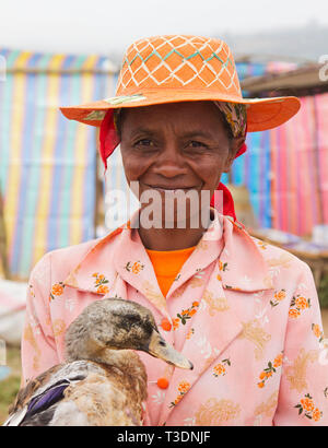 Porträt madagassische Frau mit traditionellen Strohhut und halten eine Ente auf einem Bauernmarkt, Hill Country, Madagaskar, Afrika Stockfoto