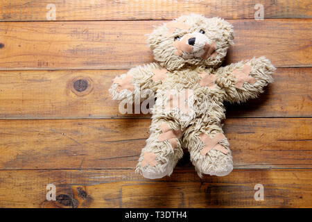 Teddybär mit Bandage auf Holz- Hintergrund Stockfoto