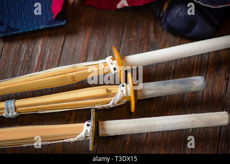 Bambus Schwerter close-up. Kendo Handschuhe, Helm und Bambus Schwert auf einem Holz- Oberfläche. Kendo Rüstung. Stockfoto