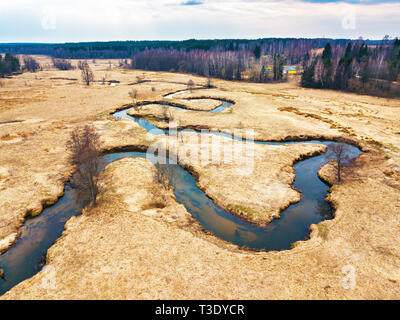 Ländliche Landschaft im April. Kleiner Fluss Sula im frühen Frühling. Luftaufnahme von Brook Kurven in einem MEDOW. Weißrussland Stockfoto