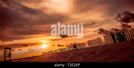 Die Sonne geht hinter einem hölzernen Lattenrost sand Zaun am westlichen Ende von Dauphin Island, Alabama. Sand Zäune sind für Erosion Control verwendet. Stockfoto