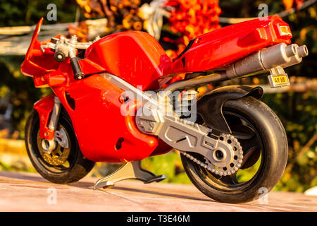 Eine Rückansicht isoliert closeup rot Spielzeug Motorrad mit kalten Farben. Foto von einem Garten eingenommen hat. Stockfoto