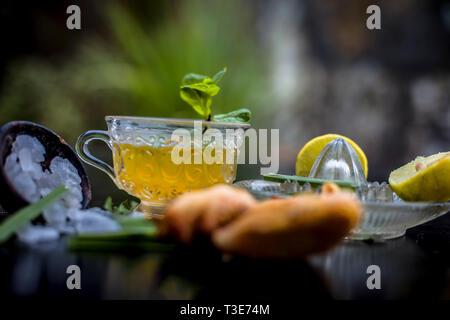 Nahaufnahme von Iced Lemon Grass Tee in eine transparente Schale auf Holz- Oberfläche mit raw Lemon Grass grüner Tee in eine Tasse und Zucker in eine Schüssel mit Ice Cube Stockfoto