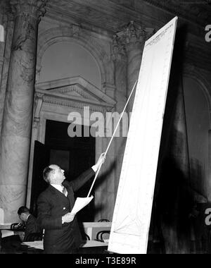 Mann in kongreßhörfähigkeit, der auf eine Linie auf einem sehr großen Diagramm kann. 1939 Stockfoto