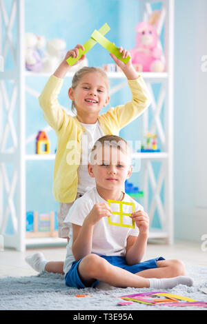 Ein kleines Mädchen mit ein Junge sitzt auf dem Boden und halten ein farbiges Papier Stockfoto