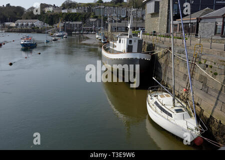 Fischerboot und Segelboot vor Porthmadog Hafenmauer Mit Yachthafen und Gebäuden im Hintergrund in Nord-wales großbritannien Stockfoto